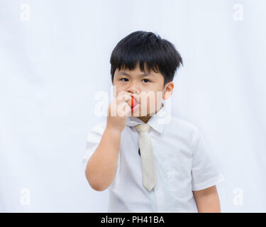 Portrait of cute Asian boy eating strawberry rouge sur fond blanc, Banque D'Images