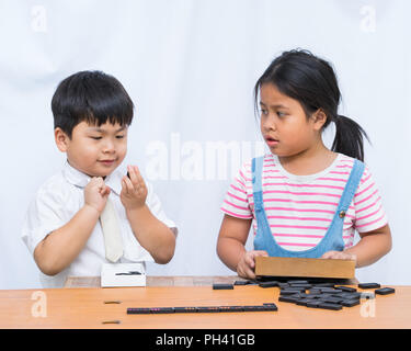 Petit garçon et fille belle lecture domeno dans table en bois sur fond blanc, Banque D'Images