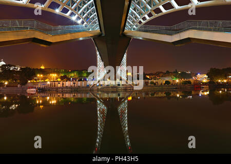 Réflexions de la passerelle moderne connu sous le pont de la paix, sur la rivière Mtkvari, de nuit, à Tbilissi, Géorgie Banque D'Images