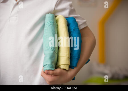 Libre d'une pile de jeans colorés dans la main de l'enfant. Le consumérisme concept. Le Shopping. Banque D'Images