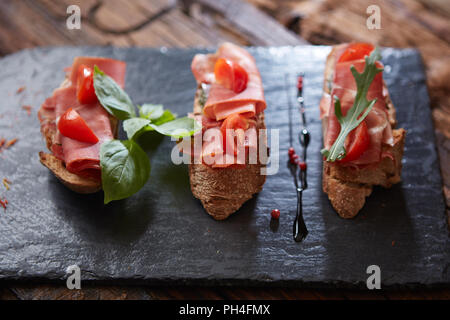 Bruschetta avec hamon et la sauce sur pierre noire Banque D'Images