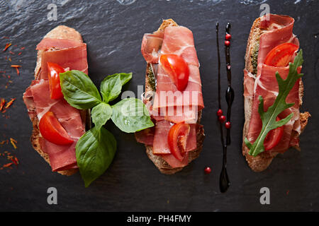 Bruschetta avec hamon et la sauce sur pierre noire Banque D'Images
