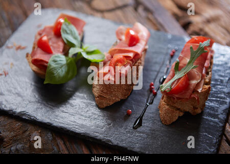 Bruschetta avec hamon et la sauce sur pierre noire Banque D'Images