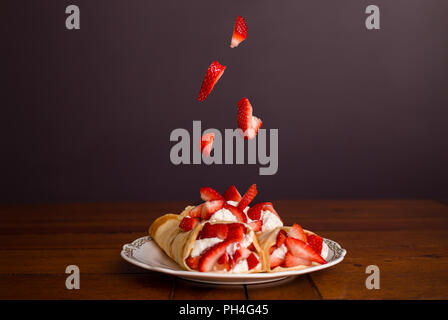 De délicieuses crêpes farcies avec fraises et crème fouettée aux fraises tomber sur le dessus de la crêpes. Banque D'Images