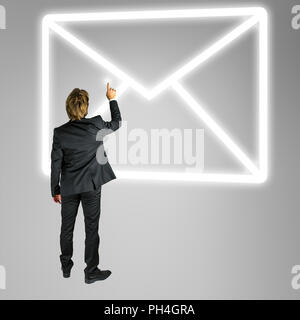 Businessman standing in front of une enveloppe mail icône sur un écran virtuel ou l'interface de contact en ligne conceptuelle et de la communication Banque D'Images