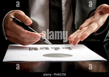 Businessman dans une réunion ou une présentation tenir un crayon dans une main et pointant avec les autres à un document sur la table devant lui, Close up vi Banque D'Images