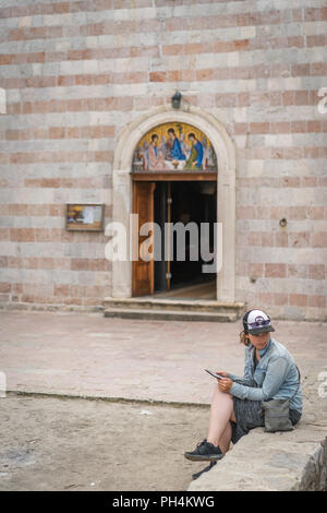 Budva, Monténégro - Avril 2018 : Woman sitting dans la cour de l'église de la Sainte Trinité Banque D'Images