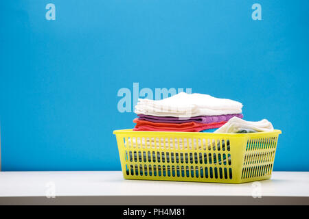 Photo de multi-couleur des serviettes de bain en jaune sur fond bleu Panier vide. Banque D'Images