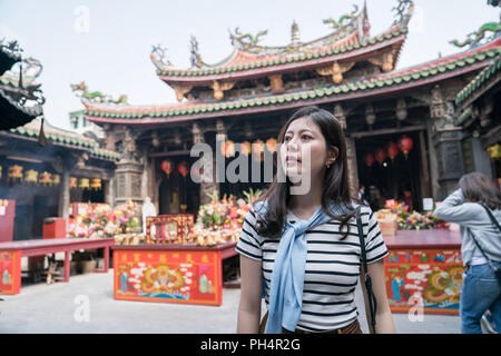 Femme Asiatique et permanent à la recherche autour du temple. Les gens d'adorer les dieux. Banque D'Images