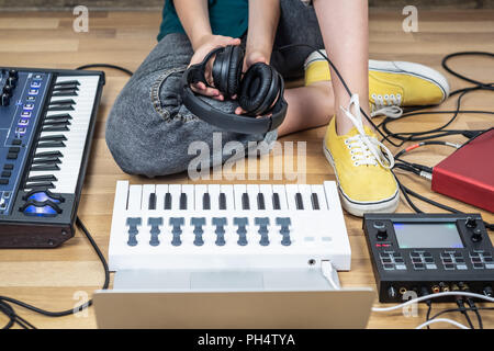 Musicien féminin se trouve dans un home studio avec les instruments électroniques modernes. Jeune femme moderne produisant la musique indépendante sur synthétiseur et contrôle numérique Banque D'Images