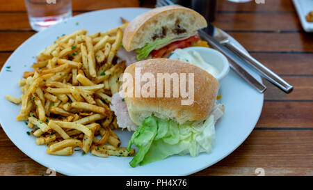 Sandwich au thon blanc sur plaque, vues de dessus, servi avec frites et sauce aigrelette, sur une table en bois, dans le cadre d'un restaurant Banque D'Images