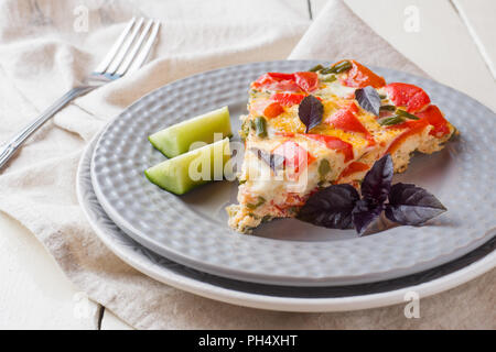 Servir l'omelette avec des légumes sur une plaque sur une table en bois blanc. Banque D'Images