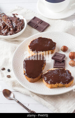 Des sandwichs avec chocolat noisettes sur la plaque. Tasse de café sur la table Banque D'Images