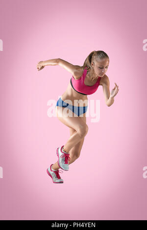 Le portrait de l'athlète de saut en hauteur ou fit woman en action je sur fond rose Banque D'Images