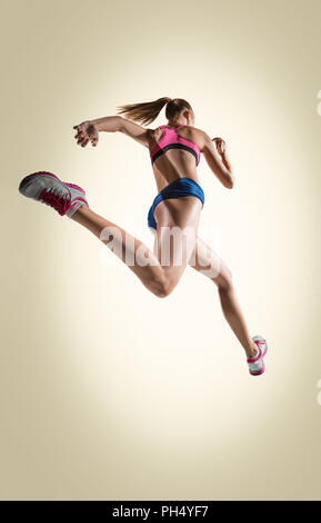 Le portrait de l'athlète de saut en hauteur ou fit woman en action isolé sur fond gris Banque D'Images