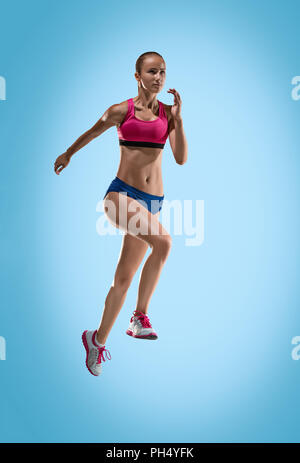 Le portrait de l'athlète de saut en hauteur ou fit woman en action je sur fond bleu Banque D'Images