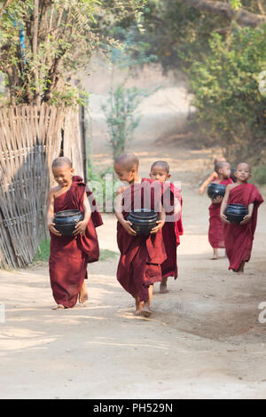 Jeunes moines sur leurs tours aumônes matin, Bagan, Myanmar Banque D'Images