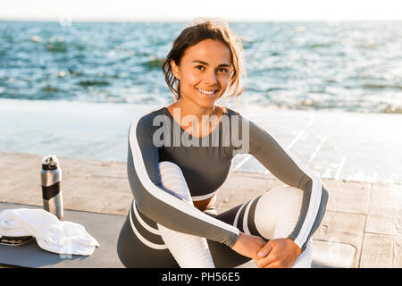 Photo de jeune femme de remise en forme en plein air sur la plage ont un reste assis à la caméra. Banque D'Images