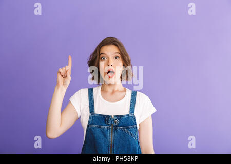 Portrait of a young woman vêtus de vêtements en denim de doigt pointé sur fond violet Banque D'Images