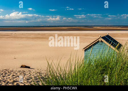 Un green beach hut avec Holkham beach derrière elle et des dunes de sable à l'avant Banque D'Images