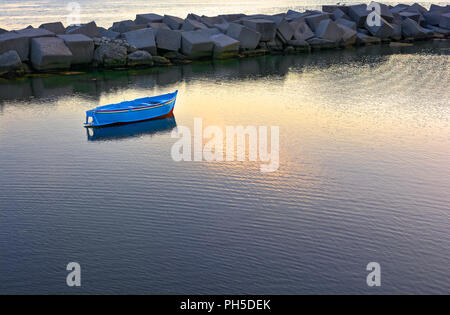 Au coucher du soleil bateau solitaire ancrée dans le petit port de pêche Banque D'Images