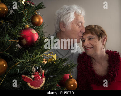 Portrait Gros plan d'un couple de personnes âgées s'embrasser par un arbre de Noël Banque D'Images