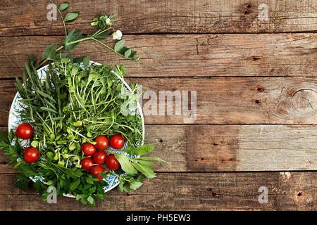 Ingrédients pour la préparation de la salade d'été. Tomate cerise, verdure, la roquette, le persil, les choux fleur, de la direction générale sur pois bleu blanc sur plaque ancienne en bois Banque D'Images