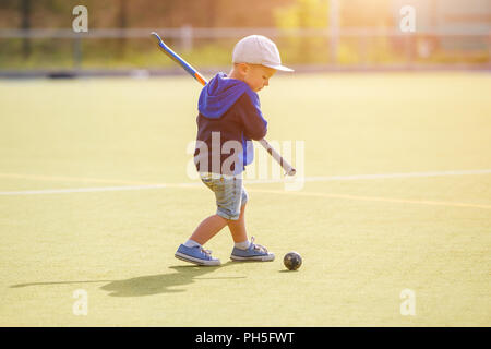 Petit Garçon jouant au hockey avec champ de formation stick sur le champ Banque D'Images