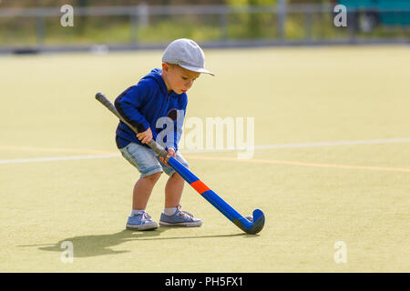 Petit Garçon jouant au hockey avec champ de formation stick sur le champ Banque D'Images