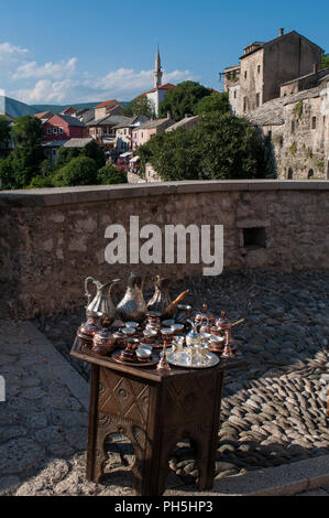 Bosnie : une petite table avec plateau en cuivre typique et café à vendre et point de vue sur les toits de Mostar avec la Mosquée Koski Mehmed Pacha Banque D'Images