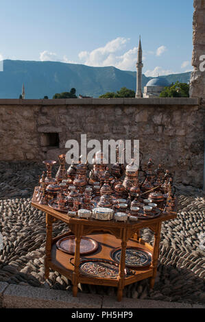 Bosnie : une petite table avec plateau en cuivre typique et café à vendre et point de vue sur les toits de Mostar avec la Mosquée Koski Mehmed Pacha Banque D'Images