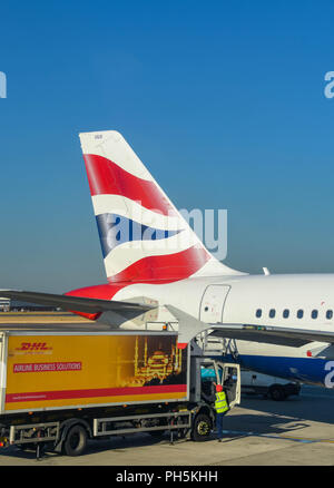 Queue d'un British Airways Airbus A320 jet à l'aéroport Heathrow de Londres. Un camion avec publicité DHL se charge de la restauration. Banque D'Images