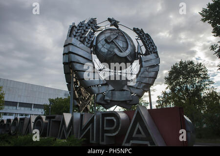 Emblème de l'état de l'Union soviétique conçu par le sculpteur soviétique Stepan Schekotikhin sur l'affichage dans le parc Muzeon Monument tombé à Moscou, Russie. L'énorme acier inoxydable emblème d'État a déjà été rétabli dans l'Avenue Leninsky à Moscou. L'inscription en russe en vertu de l'emblème d'État signifie : URSS est le fief de la paix. Banque D'Images