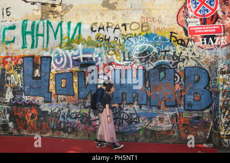 Les gens regarde le graffiti consacré au musicien rock russe Viktor Tsoi sur le mur en Krivoarbatsky Tsoi Lane à Moscou, Russie. L'énorme inscription bleu est le russe signifie : Tsoi est encore en vie. Banque D'Images
