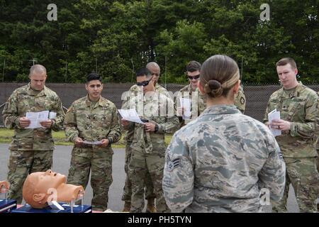 Les soldats de l'armée américaine avec le détachement de Delta, 1ère compagnie mixte de l'espace, l'Armée tactique Station sol, recevoir un exposé de l'U.S. Air Force aviateur Senior Danielle Clemons, un 35e Escadron d'opérations médicales l'administration au patient compagnon, au cours d'un Self-Aid Soins Buddy démonstration à Misawa Air Base, Japon, le 20 juin 2018. L'JTAGS exercice est une obligation annuelle pour l'armée américaine qui comprend des SABC, paintball, ruck marches et scénarios du monde réel. Banque D'Images