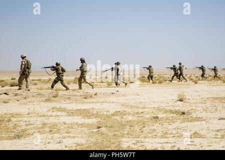 La province d'Helmand, en Afghanistan (27 juin 2018) - L'Armée nationale afghane (ANA) 215e soldats Corps lié à couvrir dans une gamme de tir réel supervisé par les instructeurs de l'ANA et conseillers du Corps des Marines des États-Unis avec la Force au sud-ouest au Camp Shorabak. C'est la première fois dans l'histoire de l'échelon régional Centre d'entraînement militaire que les militaires de l'ANA ont mené des attaques de tir réel squad avec le soutien de feu de mortiers et mitrailleuses pendant un cycle de préparation opérationnelle. Banque D'Images