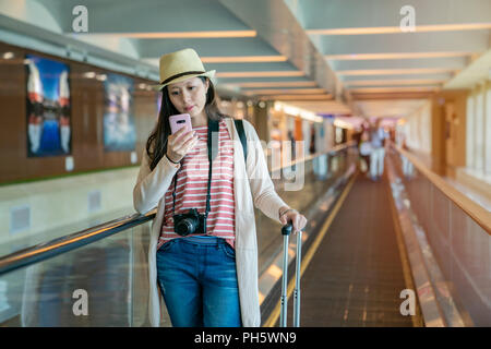 Visiteur à l'aide du smartphone sur le plancher escalator tunnel passerelle arrière-plan dans l'aéroport. Banque D'Images