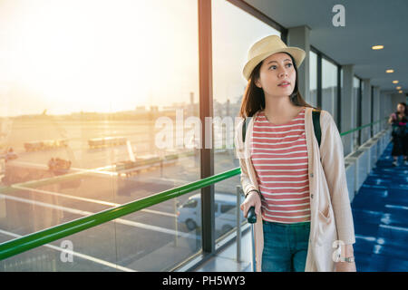 Jolie femme debout à côté de grandes fenêtres. voir dans l'aéroport. Banque D'Images