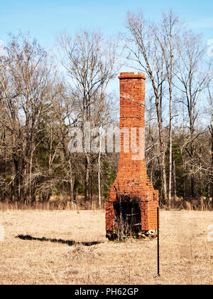 Vieille brique rustique cheminée solitaire debout à gauche dans un champ dans l'Alabama, USA. Banque D'Images