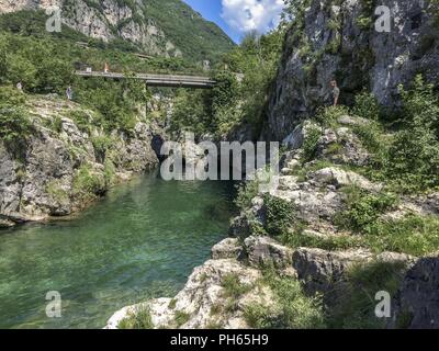 Les visiteurs sont à la recherche vers le bas des falaises qui entourent une aire de baignade populaire pour les habitants du nord de l'Italie. Les eaux glaciales qui coulent dans ces falaises sont créés par la fonte des neiges de l'entourant Dolomites. Banque D'Images