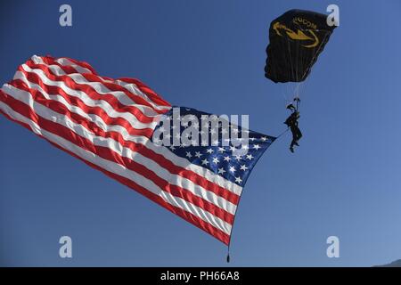 Un commandement des opérations spéciales des États-Unis de parachutistes Para-Commando dans parahutes membre aux guerriers sur l'air et de l'espace montrent Wasatch portant le drapeau américain, le 24 juin 2018, à Hill Air Force Base, dans l'Utah. Banque D'Images