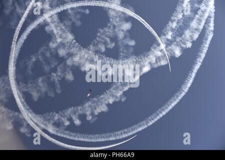 Un commandement des opérations spéciales américaines le membre de l'équipe de démonstration de parachutisme Para-Commandos effectue un hymne national flag jump alors que deux avions de voltige cercle des artistes au cours de la surcharge sur les Guerriers de l'air et de l'espace montrent Wasatch 24 juin 2018, à Hill Air Force Base, dans l'Utah. Les Para-Commandos sont composés de service actif des opérateurs spéciaux, tels que les forces spéciales de l'armée, Army Rangers, Navy SEALs, lutter contre l'Armée de l'air marin et les contrôleurs de Raiders. Banque D'Images