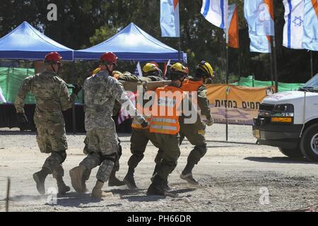 TEL AVIV, ISRAËL - Des soldats de la 19ème Force de réaction de l'amélioré CBRN et des soldats de la Force de défense d'Israël un rush de recherche et de sauvetage à une victime simulée d'ambulance d'attente au cours de l'exercice final de United Front VII à base d'entraînement de Zikim, 20 juin 2018. L'exercice final combiné les jours précédents de la formation avec un exercice réel avec les soldats d'accueil/commande. Banque D'Images