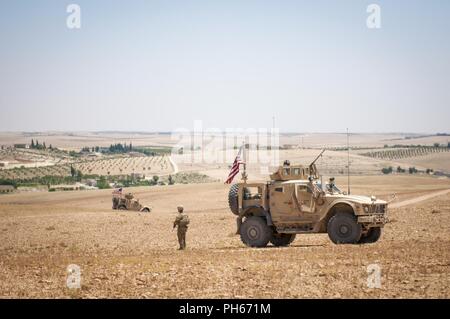 Des soldats américains d'assurer la sécurité lors d'une patrouille indépendante, coordonnée le long de la ligne de démarcation dans un village près de Manbij, Syrie, le 26 juin 2018. Les forces de la Coalition et l'armée turque a récemment commencé à patrouiller sur chaque côté de la ligne pour assurer la sécurité et la stabilité de la région. Banque D'Images