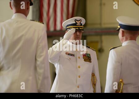 Le Capitaine Jeremy Smith rend hommage à l'arrière. Adm. David Throop, commandant de la Garde côtière canadienne 13e arrondissement, au moment où il prend le commandement du fleuve Columbia, du secteur du Capitaine William Timmons, lors d'une cérémonie tenue à la base du secteur dans la région de Warrenton, Oregon, le 28 juin 2018. La cérémonie de passation de commandement est une vieille tradition profondément enracinée dans l'histoire de la Marine et la Garde côtière canadienne, ce qui signifie un transfert total de la responsabilité d'un chef à l'autre. Banque D'Images