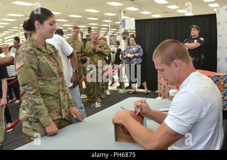 Deux fois Champion du Super Bowl, Rob Gronkowski, All-Pro tight end pour les New England Patriots, signe un football pour la CPS. Rachel Lovato, du 51e Bataillon des transmissions du Corps expéditionnaire, au cours d'une cérémonie de signature tenue le 27 juin à l'échange Principal Lewis. Gronk signé shirts, des ballons et autres éléments tout en prenant des photos avec ceux qui y ont assisté. Banque D'Images