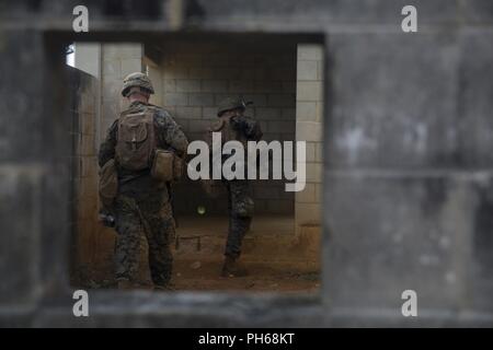 Lance le Cpl. Roi Hunter et lance le Cpl. Tanner Springer, une compagnie de fusiliers avec Echo, l'Équipe de débarquement du bataillon, 2e Bataillon, 5ème Marines, passer par une cour intérieure au cours d'un assaut sur la ville de Combat mécanisée dans le cadre de la 31e Marine Expeditionary Unit's MEU Exercice, zone centrale de formation, Okinawa, Japon, le 28 juin 2018. King est originaire de Cleveland, Ohio et Springer est originaire de Draper, Utah. Les Marines et les marins à la société Echo a effectué le dernier événement de formation de MEUEX, une attaque lancée depuis le Camp Schwab et ciblant la lutte contre la ville, partie de la région centrale de formation d'Okinawa. Marines Banque D'Images