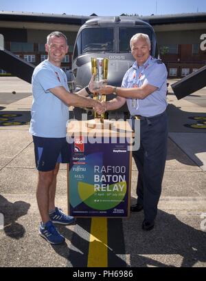 L'Escadron de la Royal Air Force. Ldr. Duncan Arnold, agent de liaison de la RAF, la Royal Air Force présente l'équipe de relais baton une plaque pour remplir leur part dans la RAF 100 Baton Relay, lors de leur visite à RAF Mildenhall, Angleterre, le 29 juin 2018. La RAF célèbre ses 100 ans et visité 100 bases au Royaume-Uni en 100 jours à célébrer 100 ans de la RAF. Banque D'Images