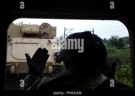 Un soldat du 2e bataillon, 5e régiment de cavalerie, 1st Armored Brigade Combat Team, 1re Division de cavalerie à l'intérieur d'un 1068A3 véhicule de commandement blindé guide le conducteur d'un 1068A3 pendant les opérations de chargement ferroviaire la gare d'Sendreni en Roumanie dans le cadre de détermination de l'Atlantique, un exercice d'entraînement durables entre l'OTAN et les forces américaines, le 27 juin 2018. Les soldats ont chargé une variété de véhicules blindés dont plusieurs M2A3 Bradley de combat, plusieurs M88A2 Hercules armored de dépannage et des dizaines de véhicules à roues pour de futures missions d'entraînement à Galati, Roumanie Zone de formation. Banque D'Images