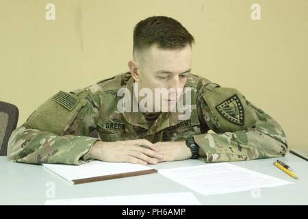 Le sergent de l'armée américaine. Zachary Green, un analyste du renseignement avec le Siège et l'Administration centrale, 38e compagnie, 1re Brigade de maintien de la commande de soutien du théâtre, se prépare à écrire un essai de réflexion de l'Armée américaine à la centrale de la concurrence meilleur Guerrier au Camp Arifjan, au Koweït, le 30 juin 2018. Pour être efficace lors d'un changement rapide de bataille les soldats doivent être mentalement forte et capable de penser rapidement. Banque D'Images